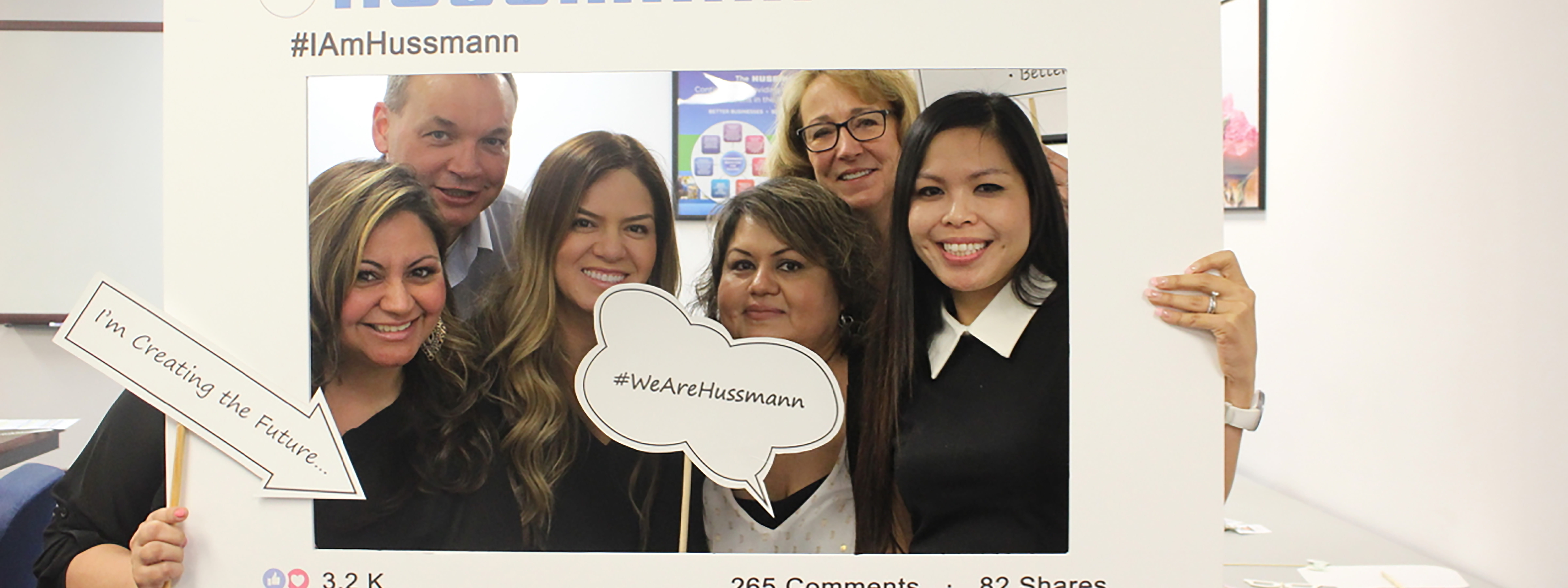 Hussmann employees smiling for photo and holding signs that say #iamhussmann and #wearehussman