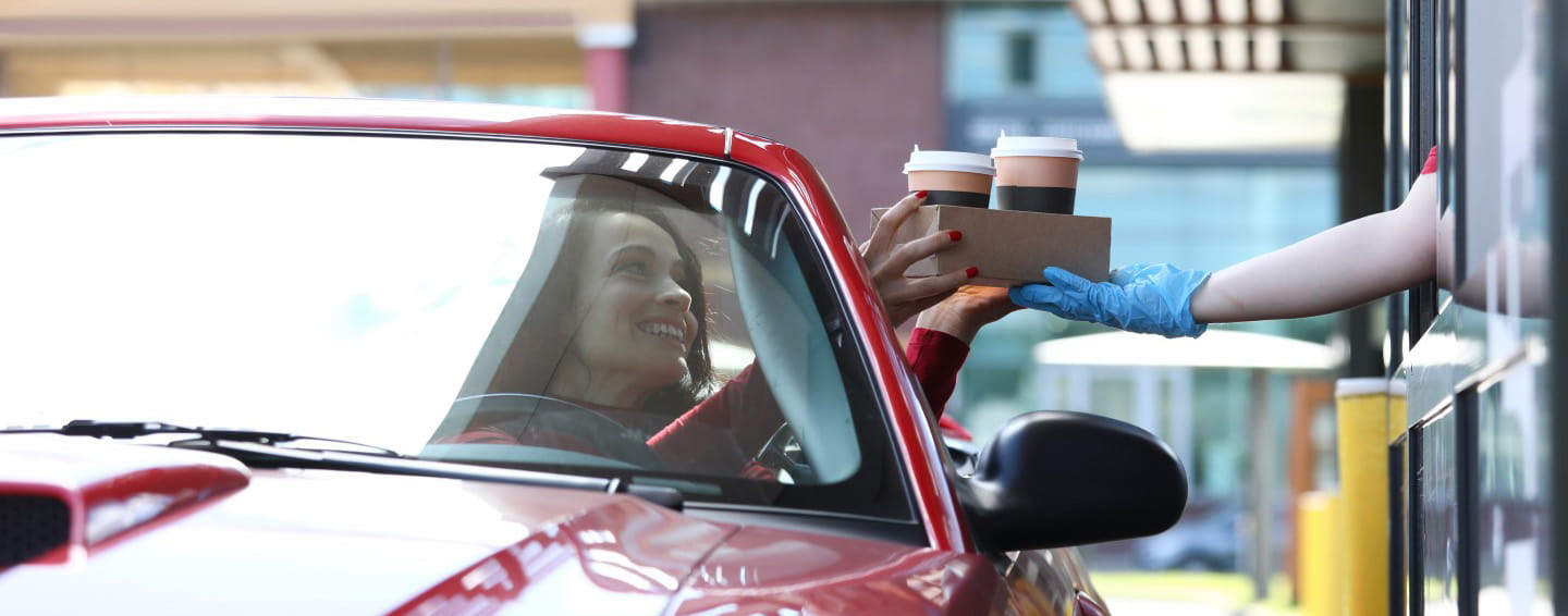 a woman buys coffee at a drive-thru